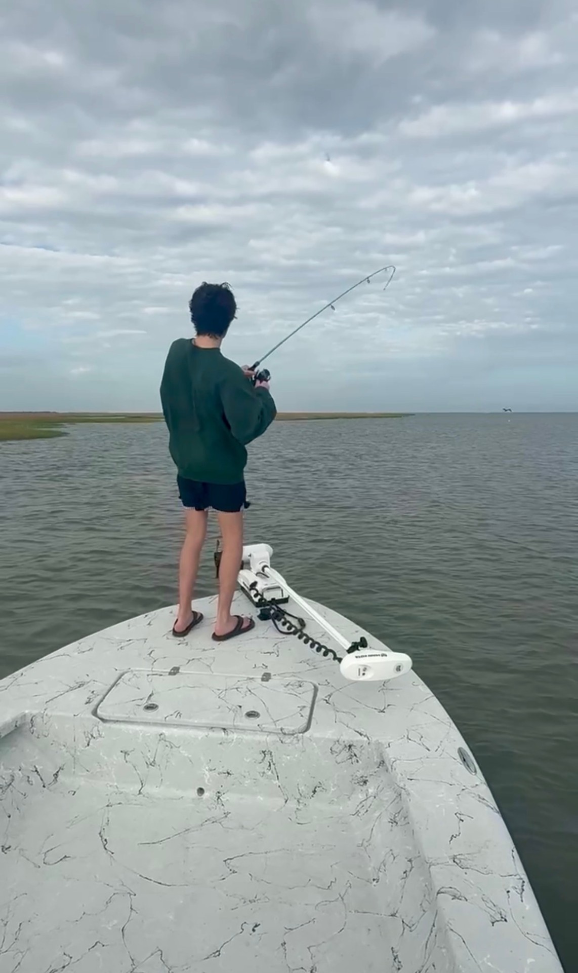 Angler with a bent rod fighting a redfish on a guided Galveston Bay fishing charter