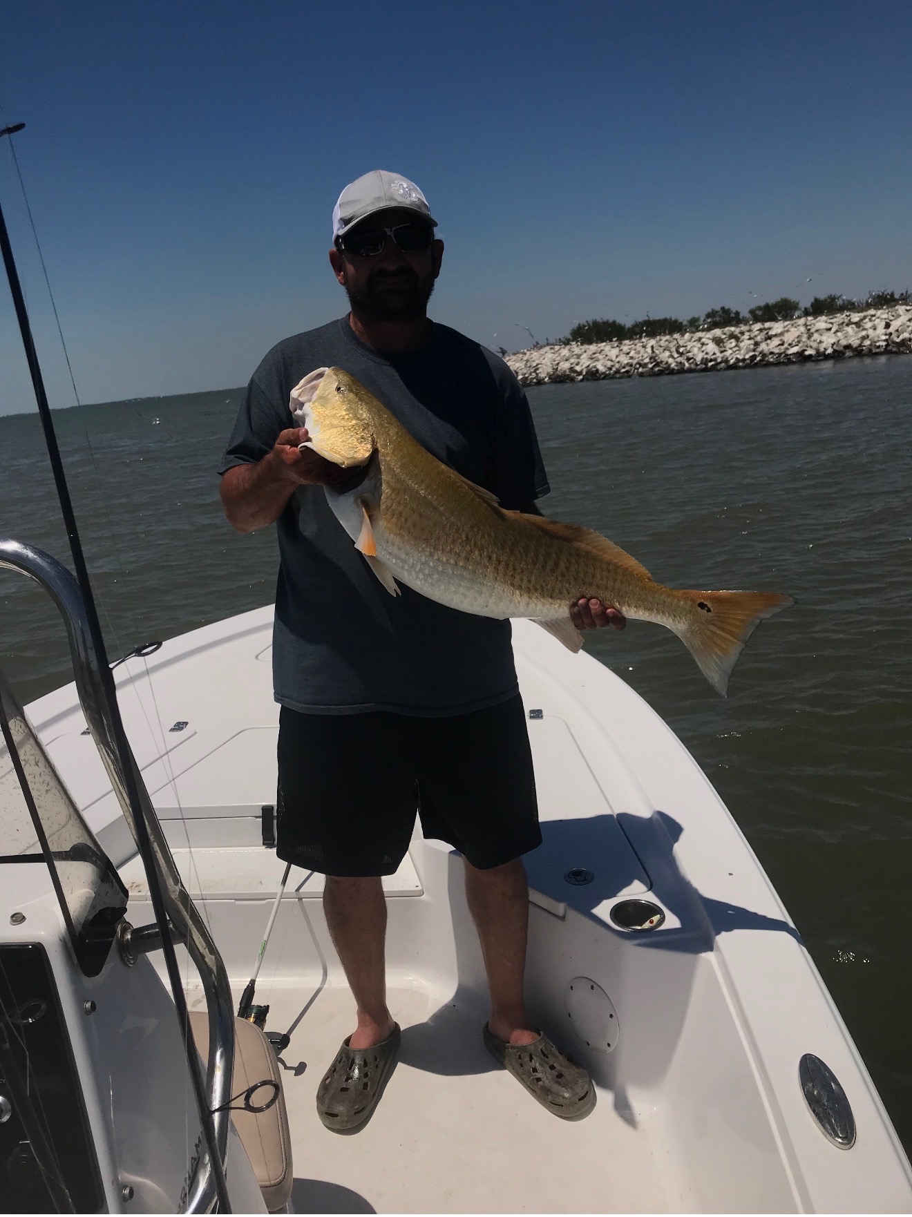 Client with a trophy redfish on the bow of the Haynie 25' Magnum on a guided Galveston Bay fishing trip