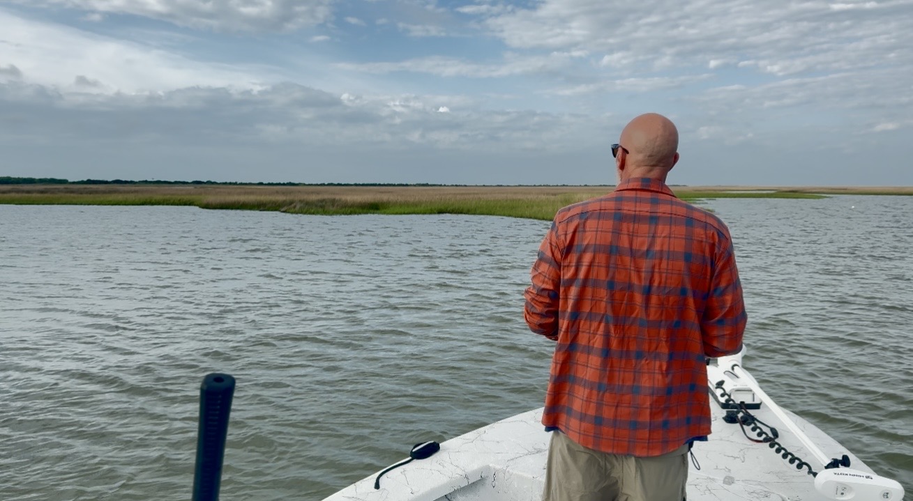 Galveston fly fishing guide poling the marsh from the bow of a Sabine skiff